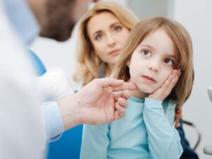 A young girl holding her cheek in pain
