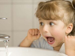 A child flossing her teeth