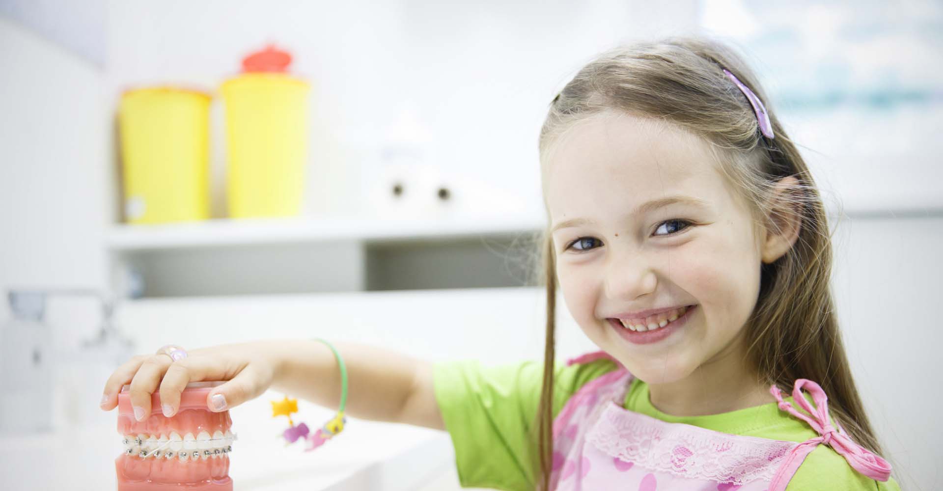 A young girl holding a model of braces